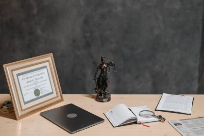 Mesa de advogado com documentos jurídicos, laptop, lupa e estátua da Justiça.