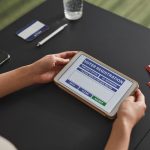 Pessoa utiliza um tablet em um posto de atendimento eleitoral.