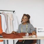 Empreendedora sorrindo enquanto trabalha em seu estúdio de moda.