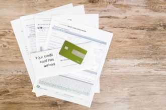 Cartão de crédito e documentos de solicitação dispostos sobre uma superfície de madeira.