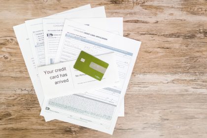 Cartão de crédito e documentos de solicitação dispostos sobre uma superfície de madeira.