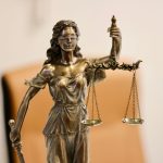 Close de uma estátua da Justiça segurando uma balança, símbolo da atividade judicial.