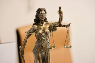 Close de uma estátua da Justiça segurando uma balança, símbolo da atividade judicial.