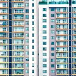 Edifício residencial moderno de vários andares, com diversas sacadas e janelas.