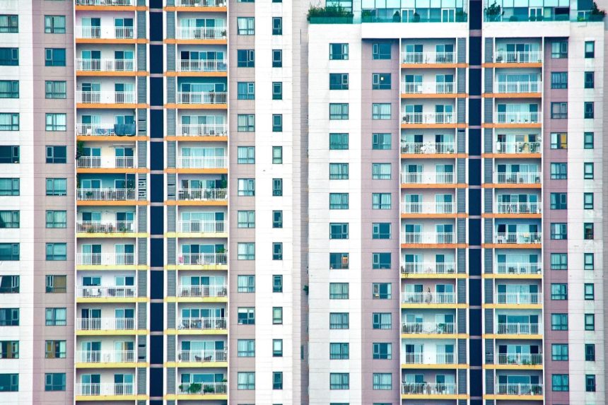 Edifício residencial moderno de vários andares, com diversas sacadas e janelas.