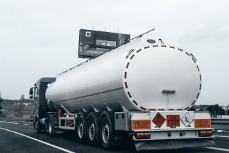Caminhão-tanque transportando combustível por uma rodovia.